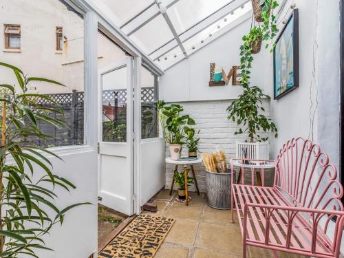 an outdoor patio with pink chairs and plants at Pass the Keys Delightful 2 Bed House a Stones Throw From Beach in Bognor Regis