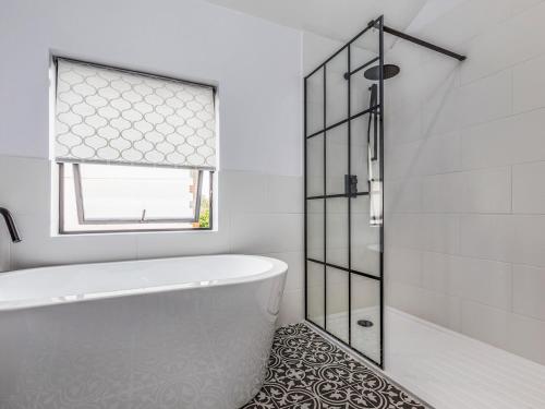 a white bathroom with a tub and a window at Pass the Keys Delightful 2 Bed House a Stones Throw From Beach in Bognor Regis