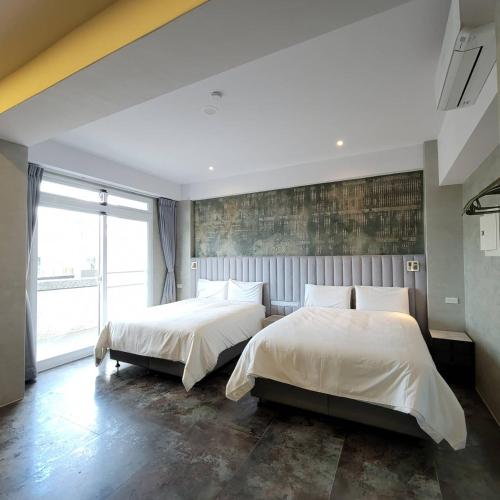a bedroom with two beds and a large window at 芙蘿拉萃旅 in Taitung City