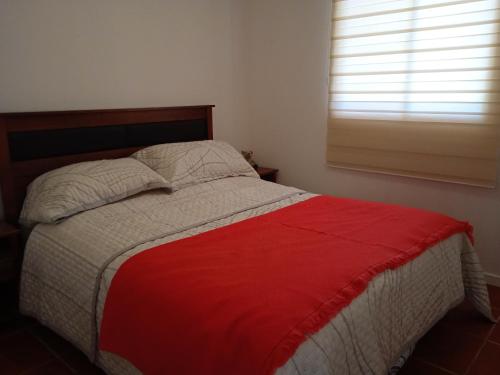 a bedroom with a bed with a red and white blanket at Hospedaje el Rosario in Angol