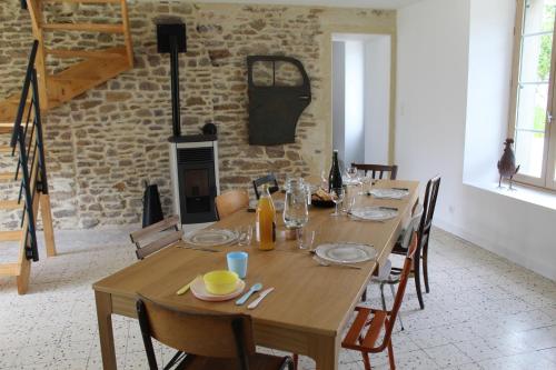 une salle à manger avec une table en bois et une cheminée dans l'établissement Gîte Le Coq Au Vert en Suisse Normande, à Hamars
