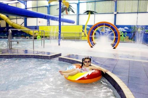 a woman laying on a raft in a swimming pool at Golden Palm Getaway's PG143 in Skegness