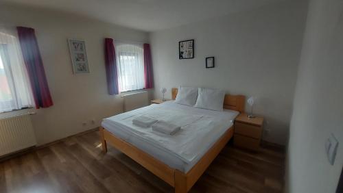 a bedroom with a bed with white sheets and two windows at Chata Zdeňka Abertamy in Abertamy