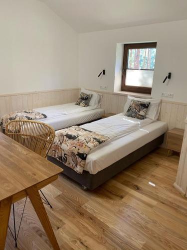 two beds in a room with a table and a window at Largo Lake Resort Kaszuby in Borsk