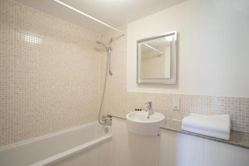 a white bathroom with a sink and a shower at Heacham Manor Hotel in Hunstanton
