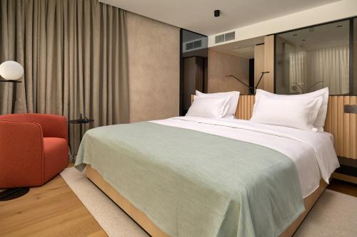 a bedroom with a large bed and a red chair at Hotel Ambasador in Split