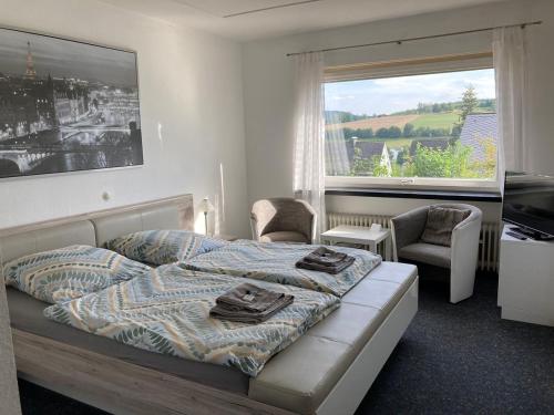 een slaapkamer met een bed en 2 stoelen en een raam bij Bed & Breakfast Weisser Stein in Schmallenberg