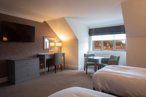 a hotel room with a bed and a desk and a television at Heacham Manor Hotel in Hunstanton