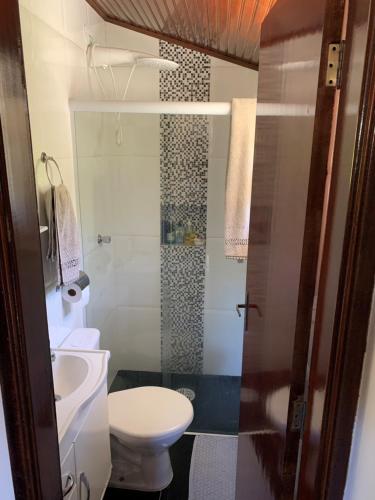 a bathroom with a toilet and a glass shower at Chalé da Araucária in Campos do Jordão