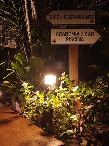 a street sign in a garden of plants with a sign at Hotel Pousada Casacolina in Búzios