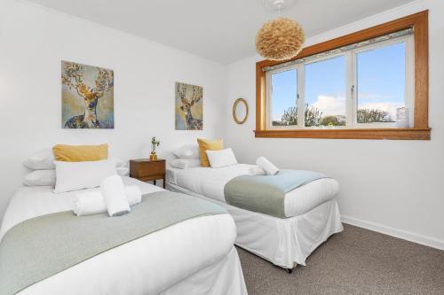 2 camas en una habitación blanca con ventana en Cozy with Character Cheerful Home with Garden at Leith Links Park, en Edimburgo