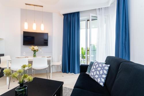 ein Wohnzimmer mit einem blauen Sofa und einem Tisch in der Unterkunft Flatbook Apartamenty - Kąty Rybackie Marina in Kąty Rybackie