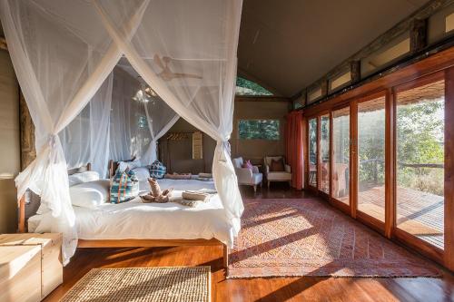 a bedroom with a bed with a canopy at Amber River Camp in Okavango Delta