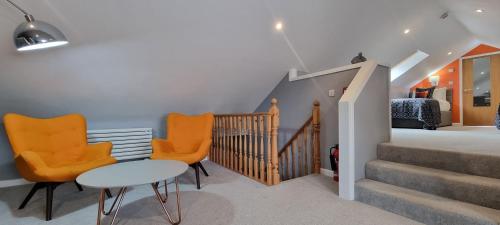a living room with orange chairs and a staircase at LLety Cynin in Llangynin