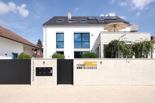 een wit huis met een bord op een hek bij Home and Business - Wohnen auf Zeit in Burgau