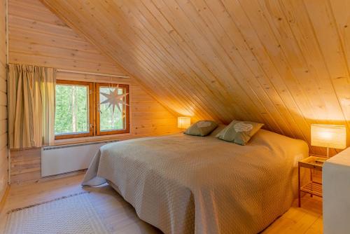 a bedroom with a bed in a wooden cabin at Patalaiska Cottages in Ruokolahti