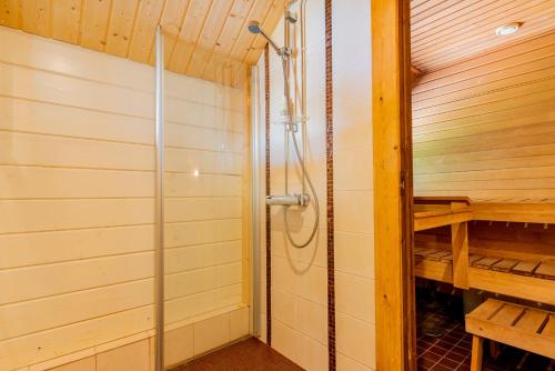 a shower in a sauna with a wooden wall at Patalaiska Cottages in Ruokolahti