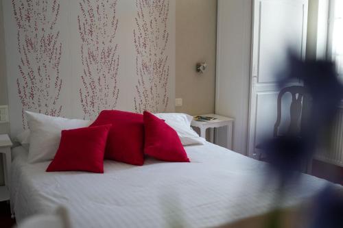 a bed with two red pillows on top of it at Hôtel Picardia in Saint-Valery-sur-Somme