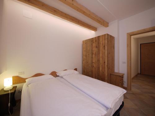 a bedroom with a white bed and a wooden cabinet at Appartamenti Home Service in Arabba