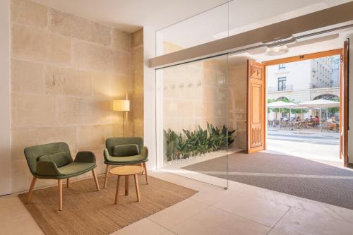 two chairs and a table in front of a glass door at Eurostars Pórtico Alicante in Alicante