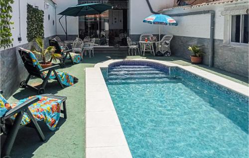 a swimming pool with chairs and an umbrella next to a building at 5 Bedroom Awesome Home In Trasmulas, Granada in Trasmulas