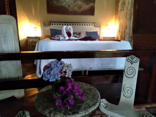 a bedroom with a bed and a table with flowers at Vista Linda Hotel in Itatiaia