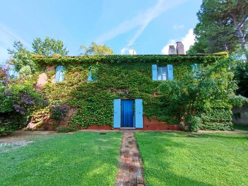 an ivy covered house with a blue door at Alloggio Al San Girolamo in Longiano