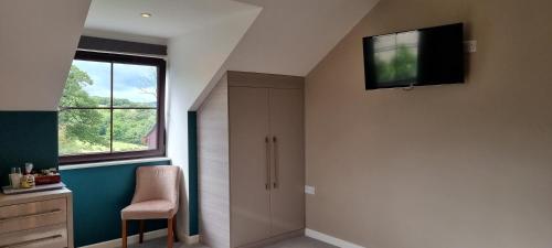 a room with a tv on the wall and a chair at LLety Cynin in Llangynin