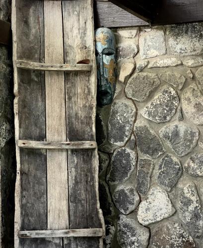 a wooden door with a mask on a stone wall at Firefly Estate Bequia in Crescent Beach