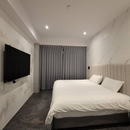 a bedroom with a white bed and a flat screen tv at 芙蘿拉萃旅 in Taitung City