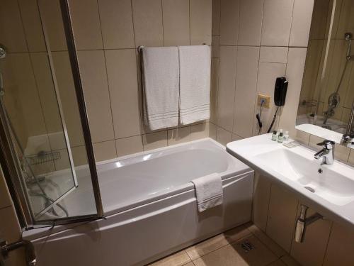 Baño blanco con bañera y lavamanos en Hotel Franco Yaounde en Yaundé