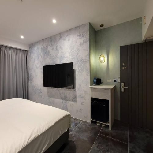 a bedroom with a bed and a tv on a wall at 芙蘿拉萃旅 in Taitung City