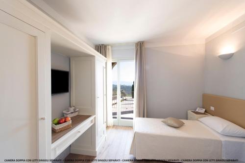 a bedroom with a bed and a tv and a window at Agriturismo Fattoria di Monticello in San Venanzo