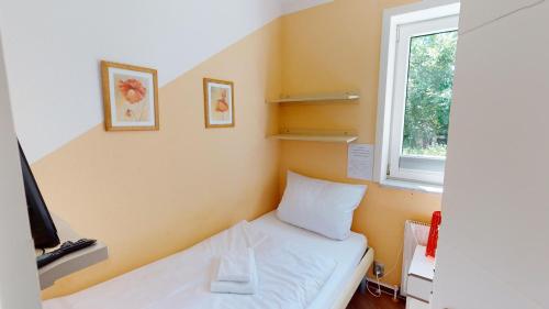 ペルツァーハケンにあるNeuKlosterhof App. 01のベッドと窓が備わる小さな客室です。