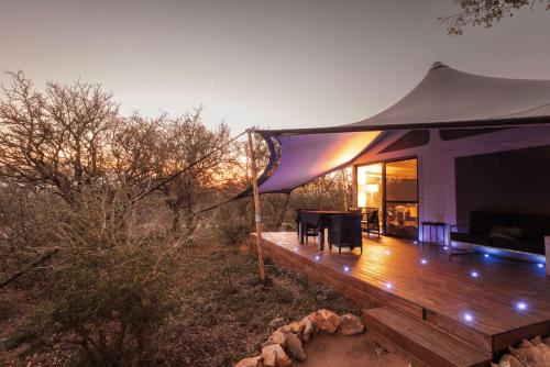 a tent with a table and chairs on a wooden deck at Oase by 7 Star Lodges - Greater Kruger Private 530ha Reserve in Hoedspruit