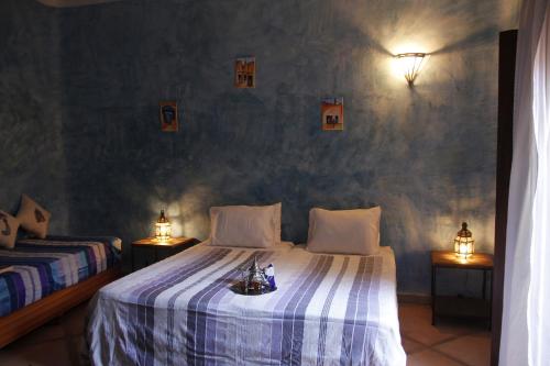 1 dormitorio con 2 camas y 2 luces en la pared en Riad Azenzer en Marrakech