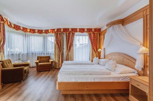 a bedroom with a large bed and a chair at Garni Hotel Franca b&b in Selva di Val Gardena