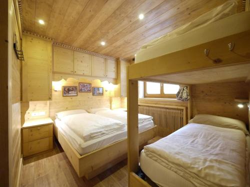 two bunk beds in a room with wooden walls at Appartamenti Home Service in Arabba