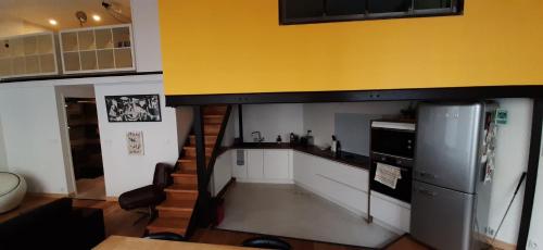 Il dispose d'une cuisine avec un réfrigérateur et un mur jaune. dans l'établissement Duplex industriel au coeur de Lyon, à Lyon