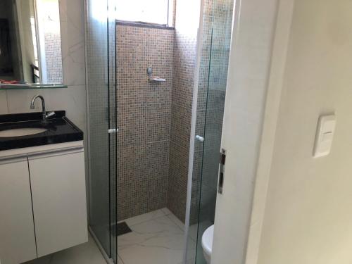 a bathroom with a glass shower with a sink at Diversão, férias, casa na praia de cumbuco. in Caucaia