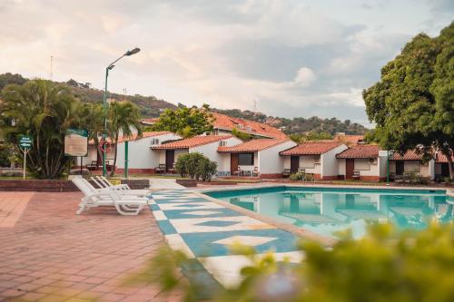 uma piscina num resort com cadeiras e árvores em Hotel Faranda Bolivar Cucuta, a member of Radisson Individuals em Cúcuta