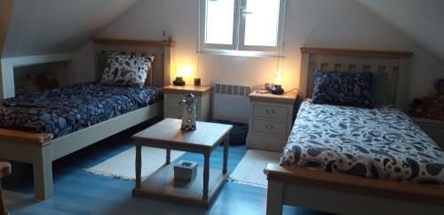 1 dormitorio con 2 camas, mesa y 2 lámparas en Les Ondines, en Estréelles