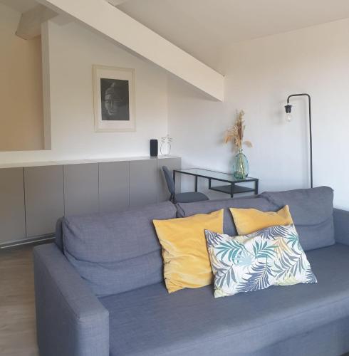 un canapé bleu avec des coussins jaunes dans un salon dans l'établissement Duplex sur les étangs de Peyriac de Mer, à Peyriac-de-Mer