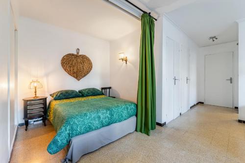 a bedroom with a bed and a green curtain at Le Marignan- Studio plein centre in Cassis