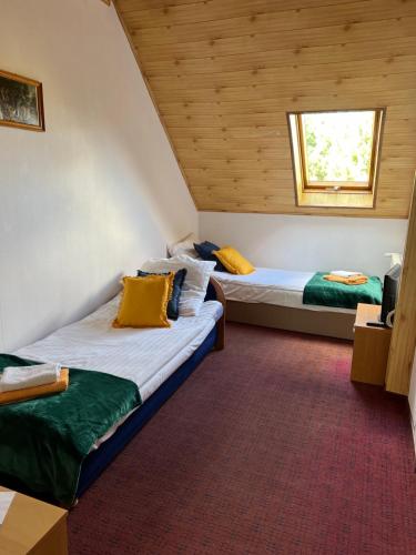 two beds in a room with wooden ceilings at Zajazd Reczyn - Nowy Reczyn 16 