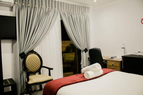 Schlafzimmer mit einem Bett, einem Schreibtisch und einem Fenster in der Unterkunft Pitikwe Hill Guesthouse in Lobatse