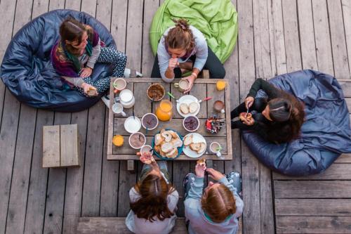 Un gruppo di persone seduti intorno a un tavolo che mangiano cibo di Compay Hostel La Pedrera a La Pedrera