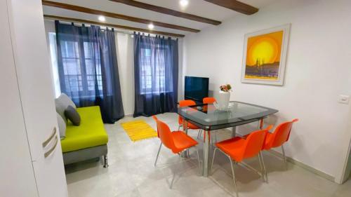Grandhouse City Apartament في بازل: غرفة معيشة مع طاولة زجاجية وكراسي برتقالية