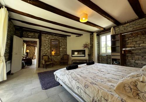 1 dormitorio con 1 cama grande y pared de piedra en Presbytère de Chauffour-sur-Vell en Chauffour-sur-Vell