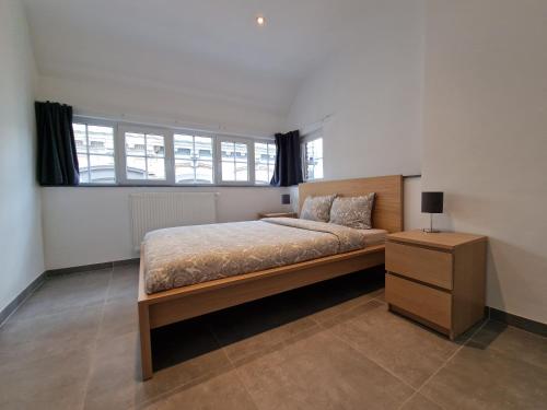 a bedroom with a bed and a nightstand and windows at Appart-Hotel Léopold Liège Centre in Liège